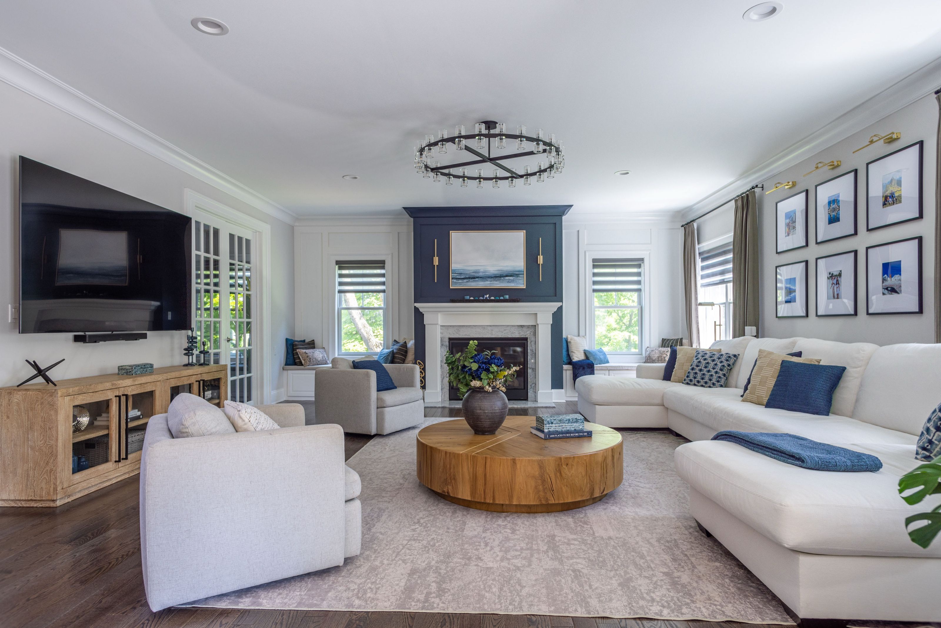 Transitional family room with a marble fireplace flanked by custom-built benches, a light layered sectional, soft gray swivel chairs, a round wood coffee table, and a soft gray and cream rug.