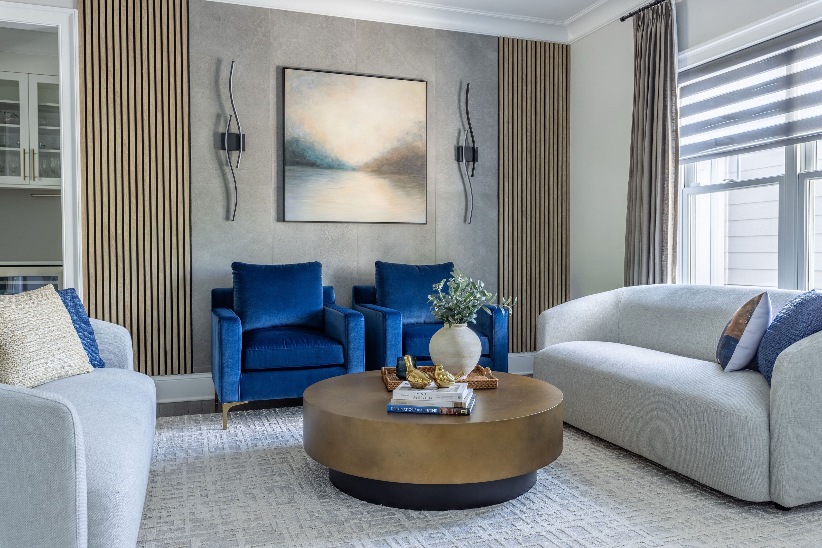 Transitional sitting room with blue upholstered chairs against decorative wood fluted wall paneling.