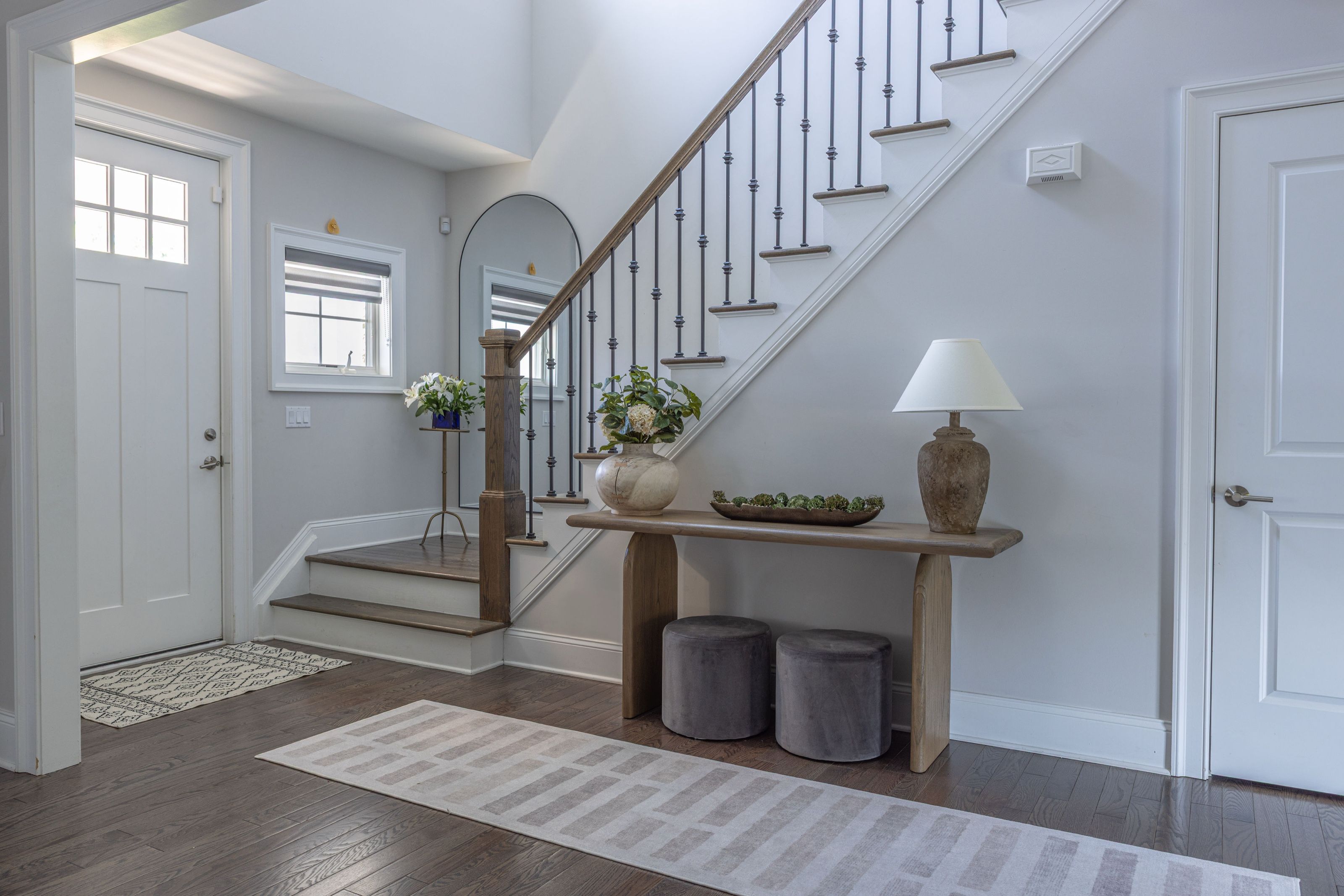 Entryway viewed from the front door, showing the staircase and console table beneath an arched mirror.