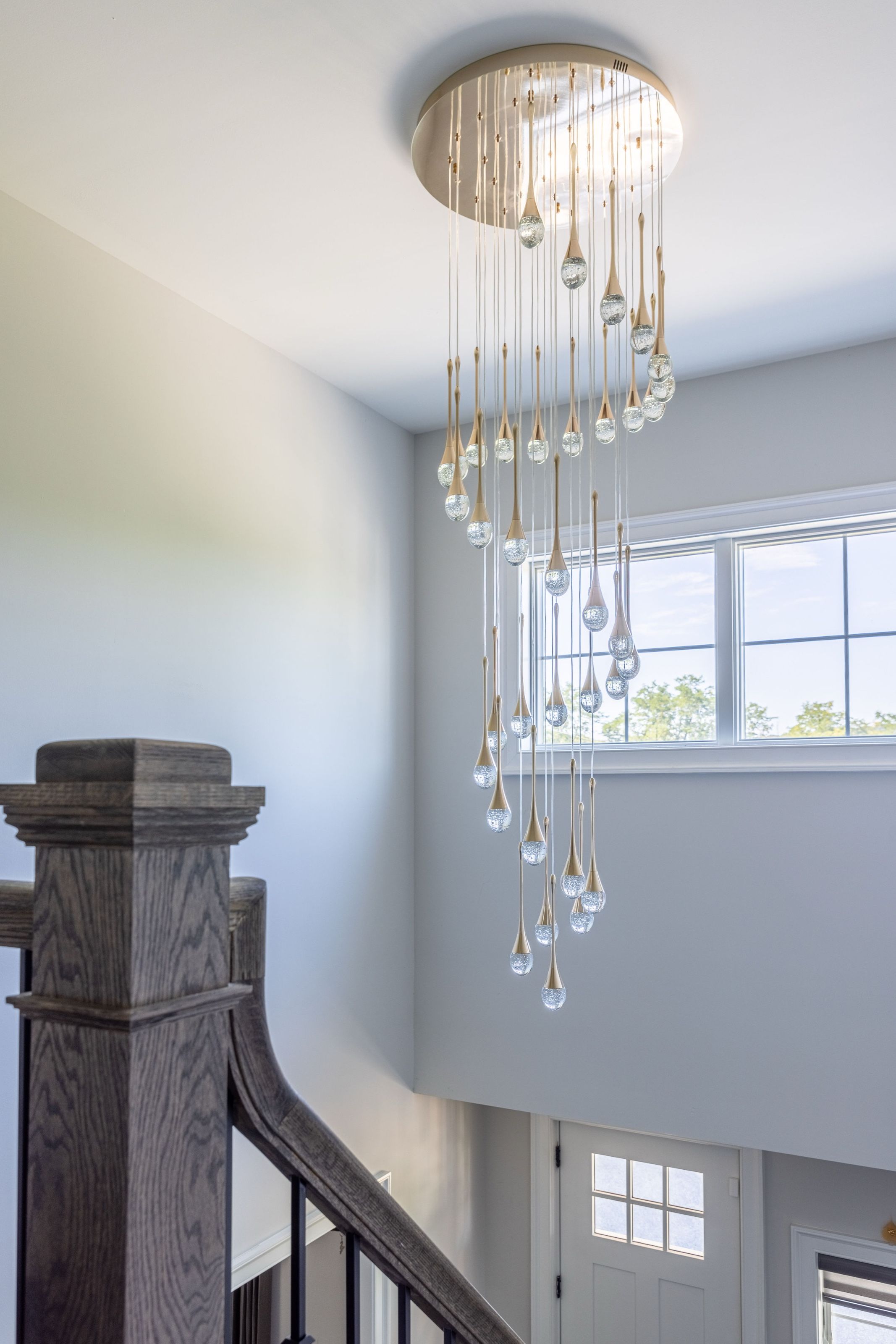 Staircase with a cascading crystal chandelier suspended above a turned wood newel post.