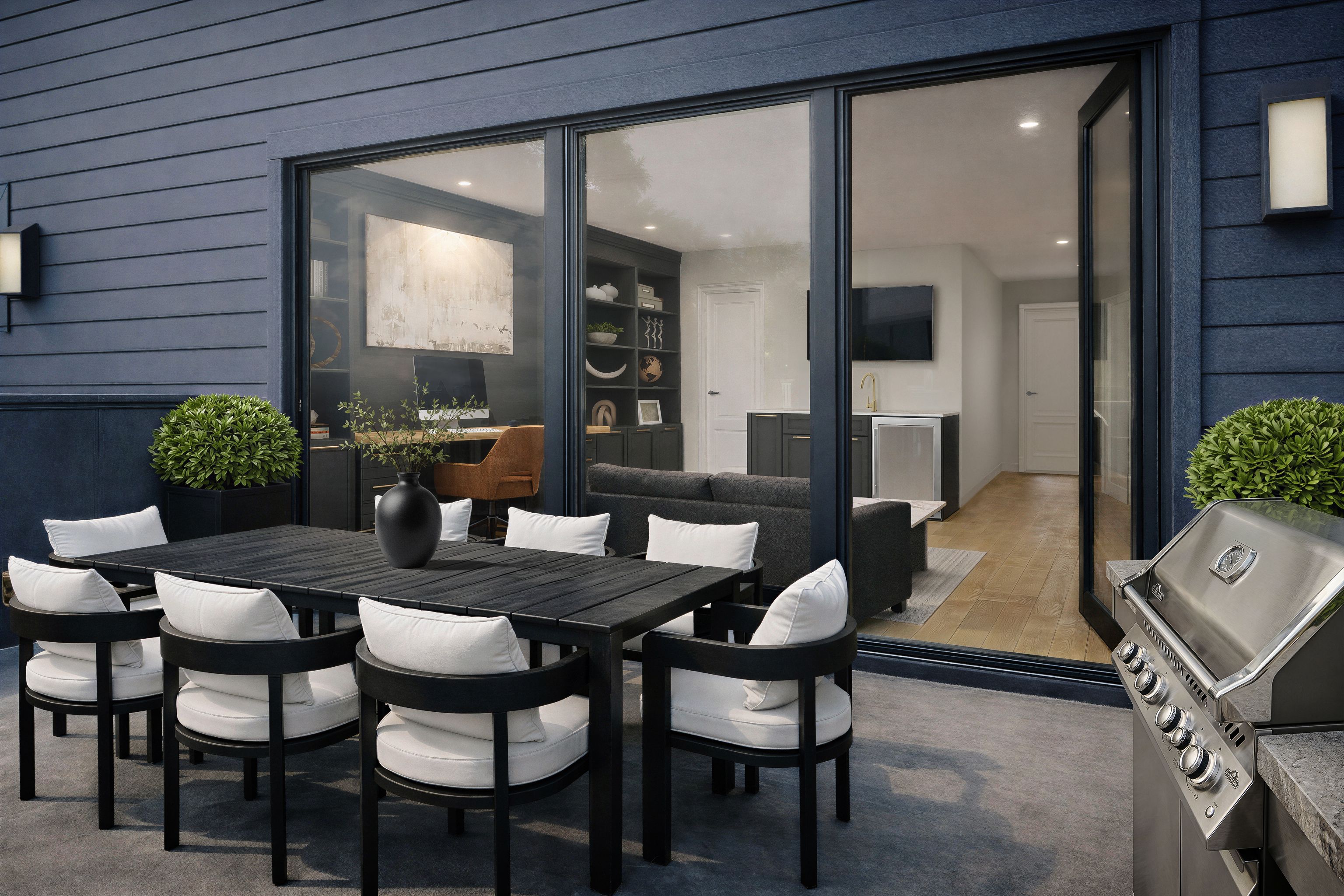 Outdoor deck with a dining table, grill and greenery, looking toward the interior of a contemporary Philadelphia townhouse through sliding glass doors.
