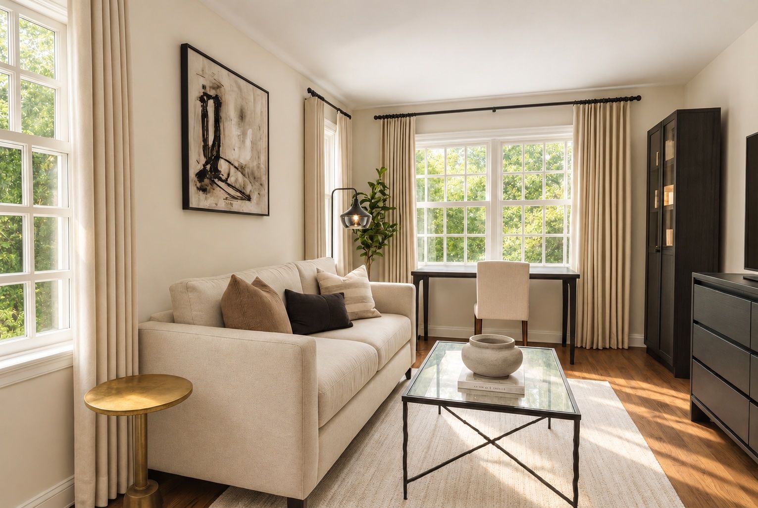 Multipurpose home office and guest room with a pale sofa, glass coffee table, desk area, and illuminated storage cabinet.