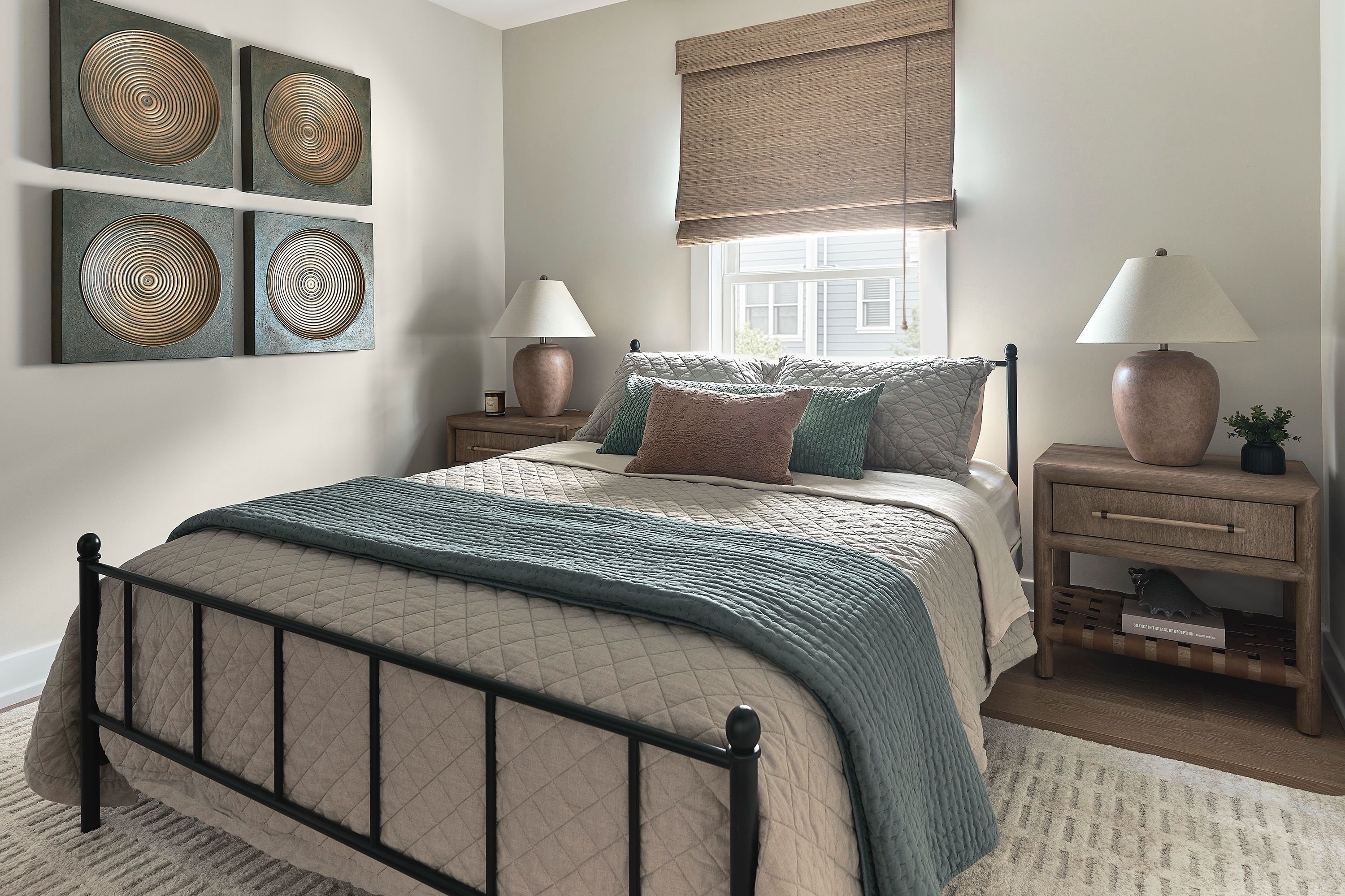 Guest bedroom with a black iron bed, wood nightstands, and four framed decorative discs above the bed.