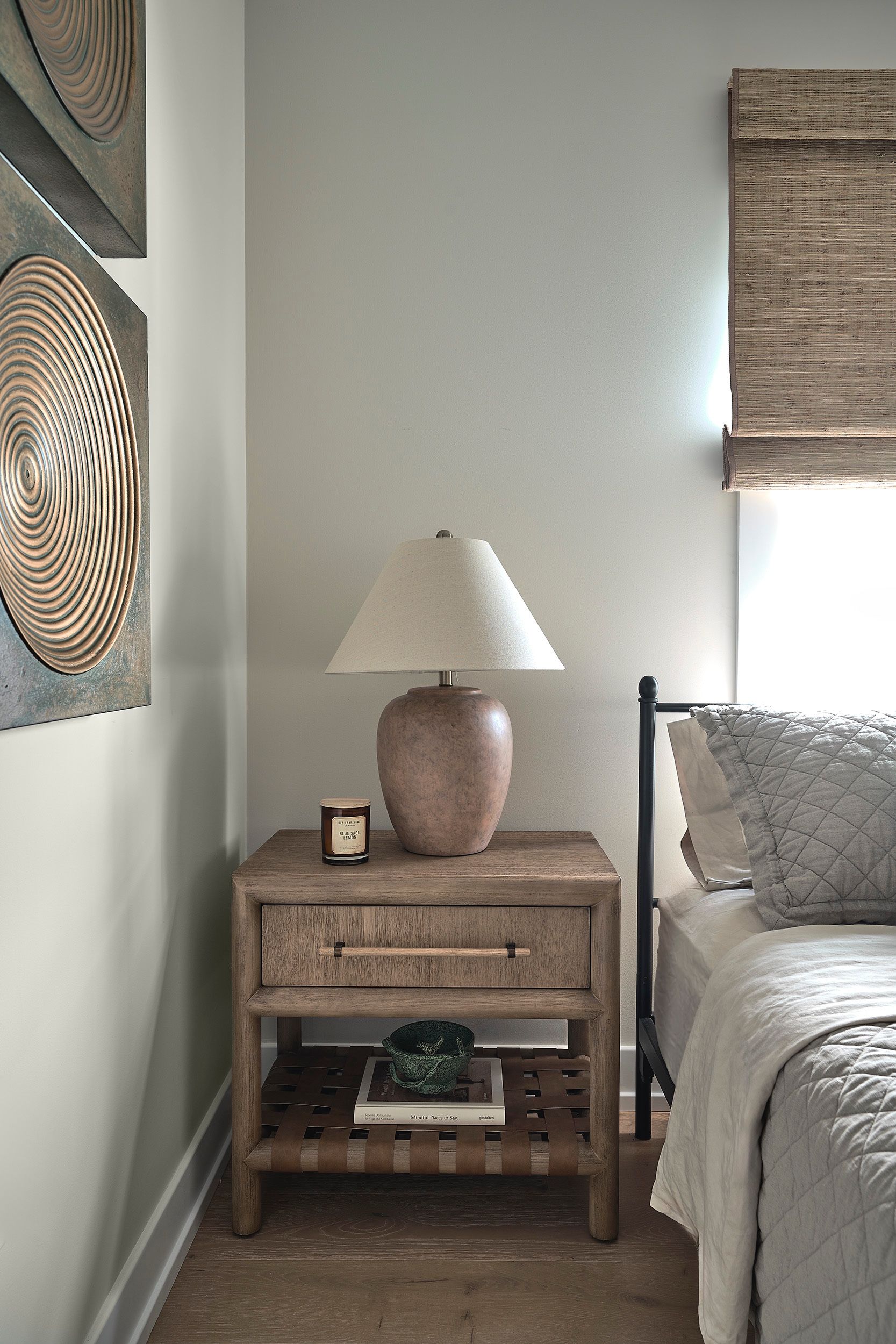 Coastal bedroom bedside vignette with a lamp, wood nightstand, and framed decorative discs.
