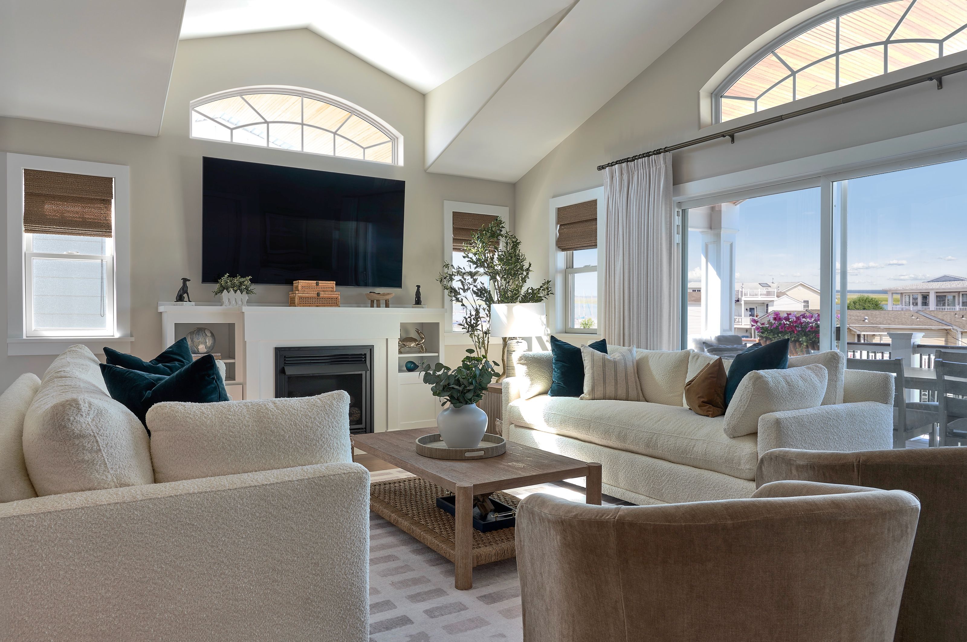 Coastal living room with white sofas, a vaulted ceiling, custom woven wood shades, and sliding glass doors opening to the deck in a Cape May County, New Jersey home.