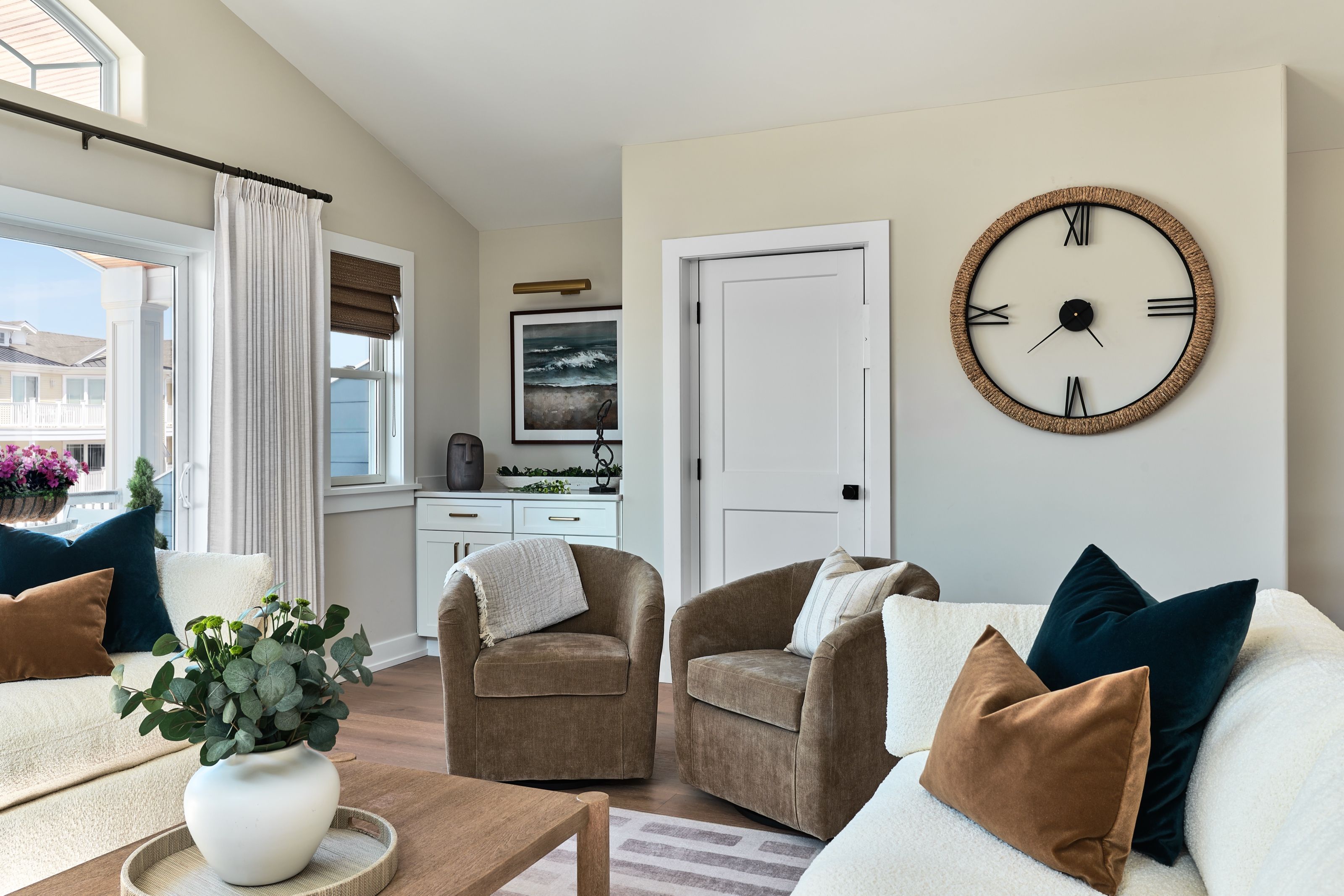 Living room seating area with two swivel chairs and a round wall clock.