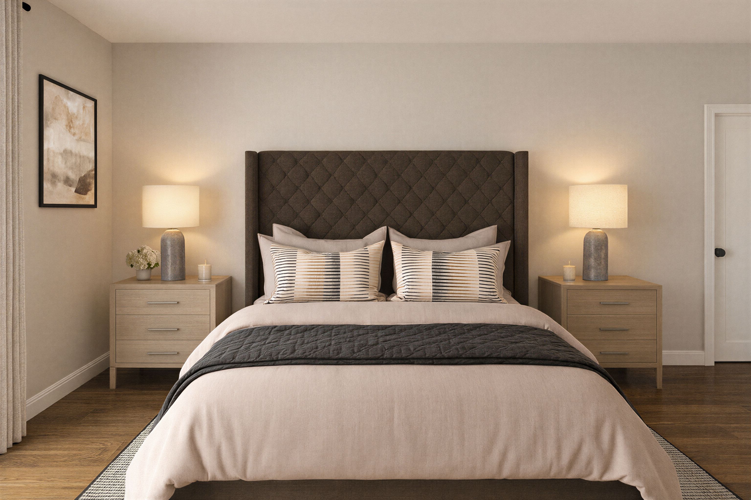 Bedroom bedside vignette with framed artwork above a lamp and nightstand beside an upholstered headboard.