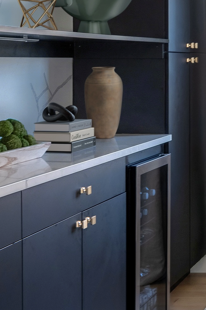 Custom dining room cabinetry featuring a stone vase, decorative books, and an integrated wine refrigerator.