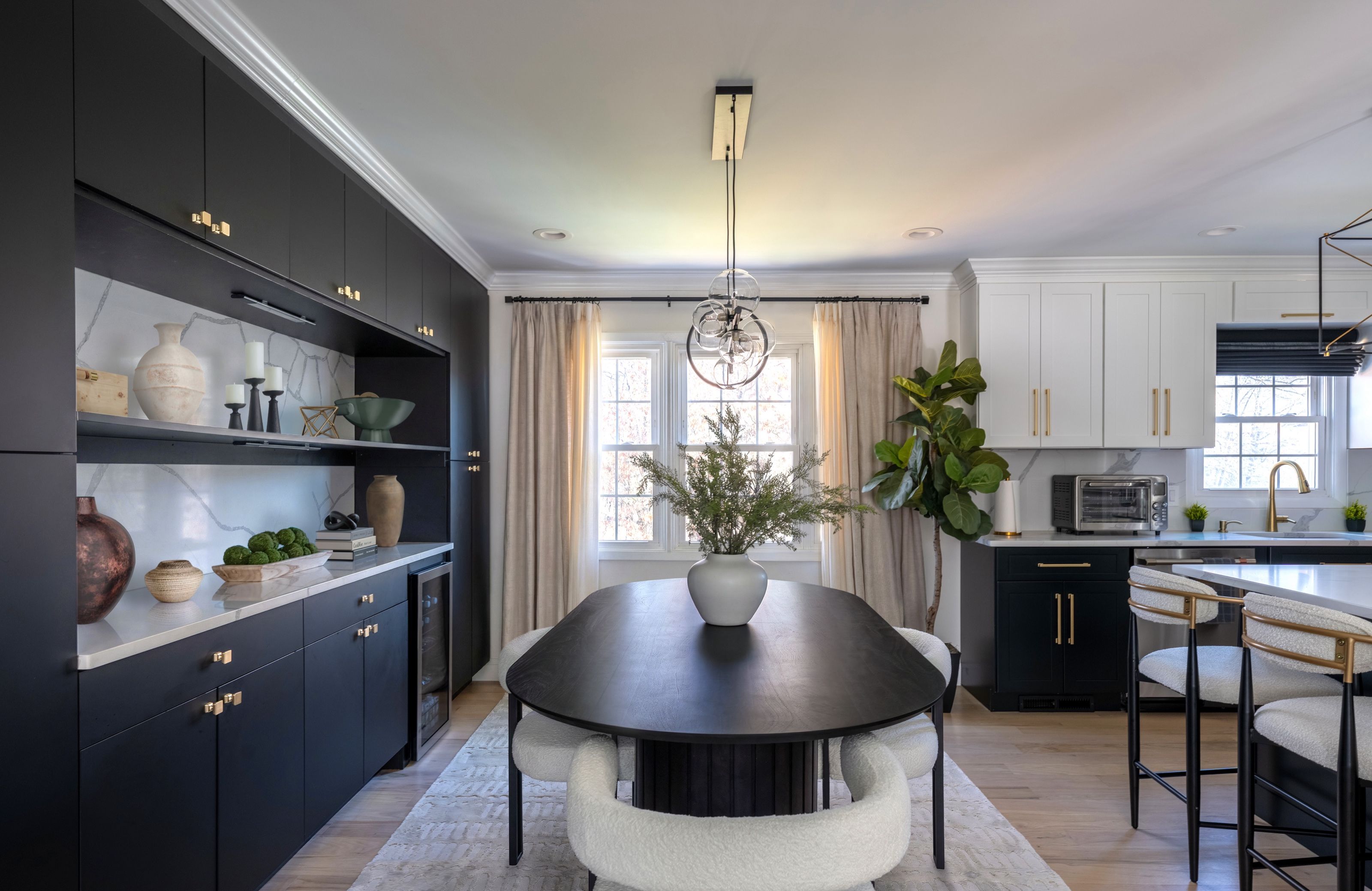 Dining room with custom black built-in cabinetry, lighted display shelves, an oval dining table, and a soft textured, washable cream rug.