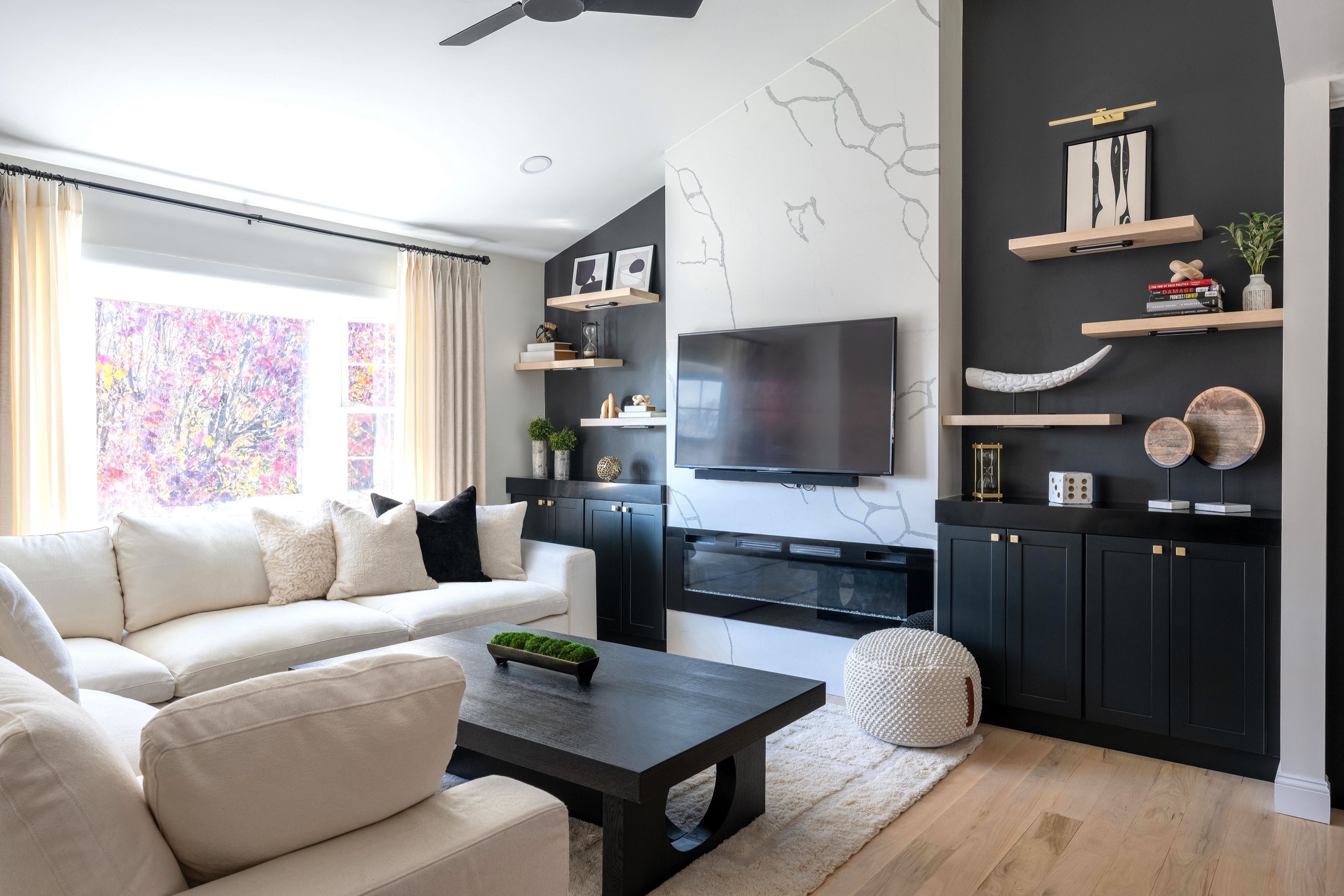 Transitional living room with a cream sectional, black coffee table, and custom dark cabinetry flanking a built-in fireplace wall with a mounted television.