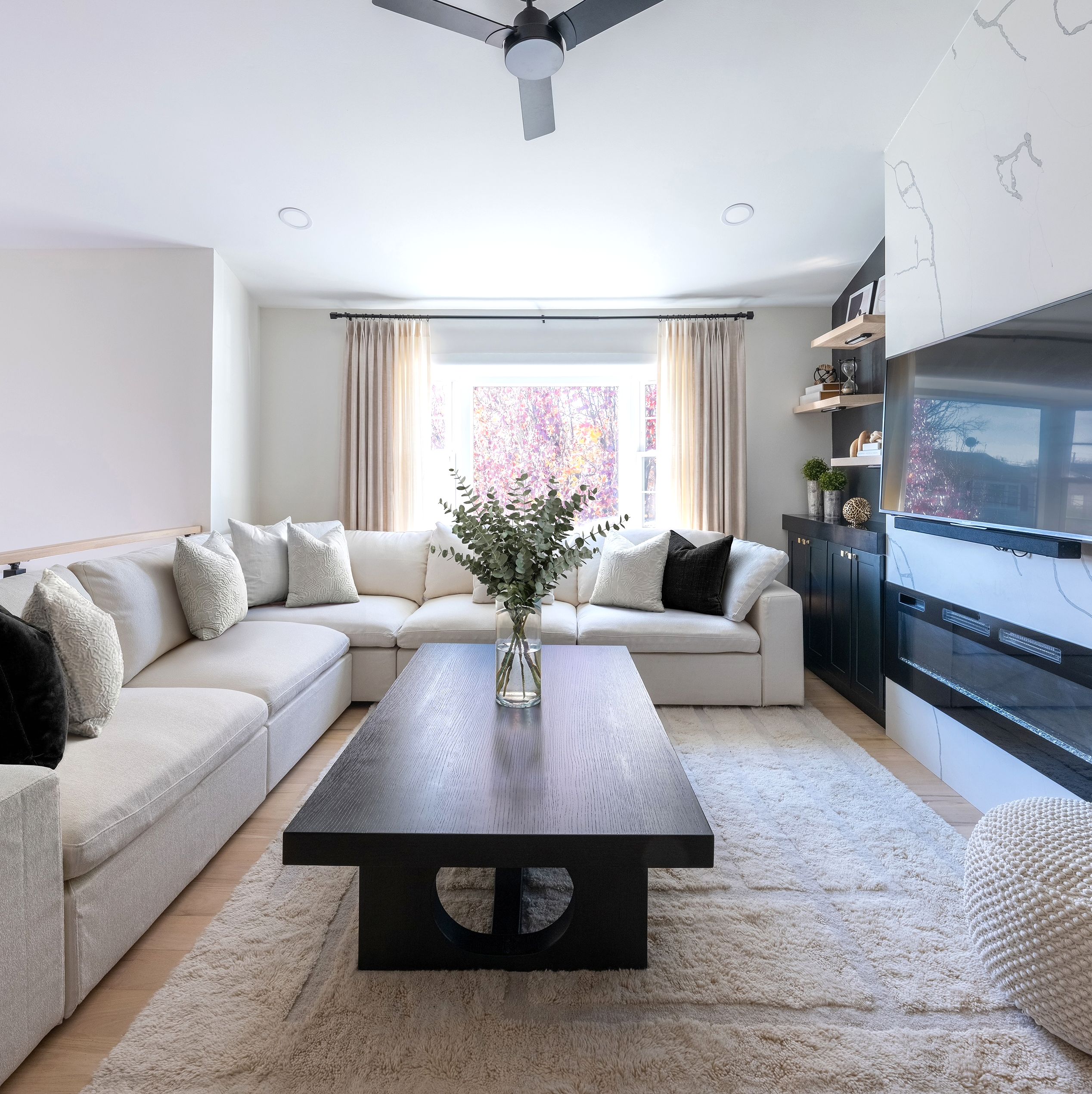 Living room with a modular sectional arranged around a long black coffee table, viewed from the opposite side of the room.